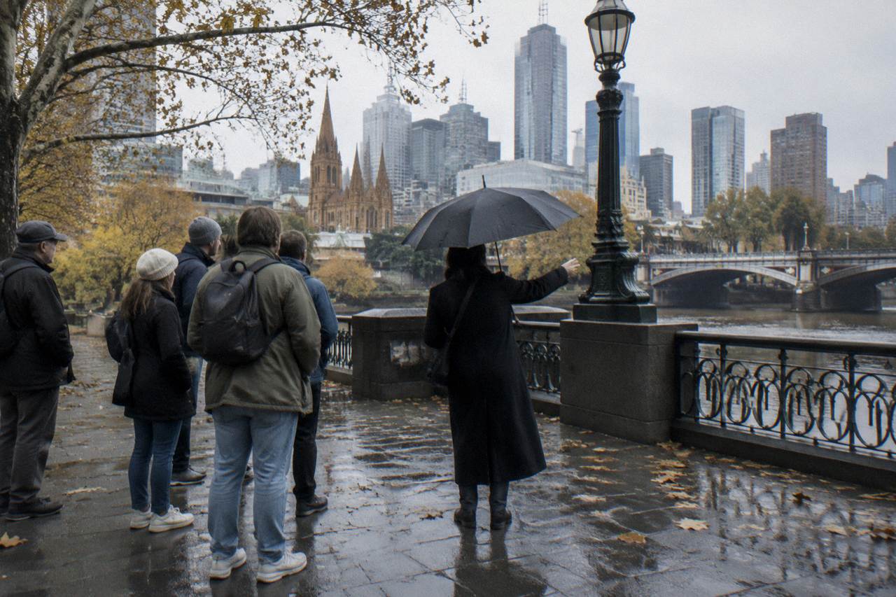 A small group of tourists listening to a guide holding an umbrella on a Melbourne city street