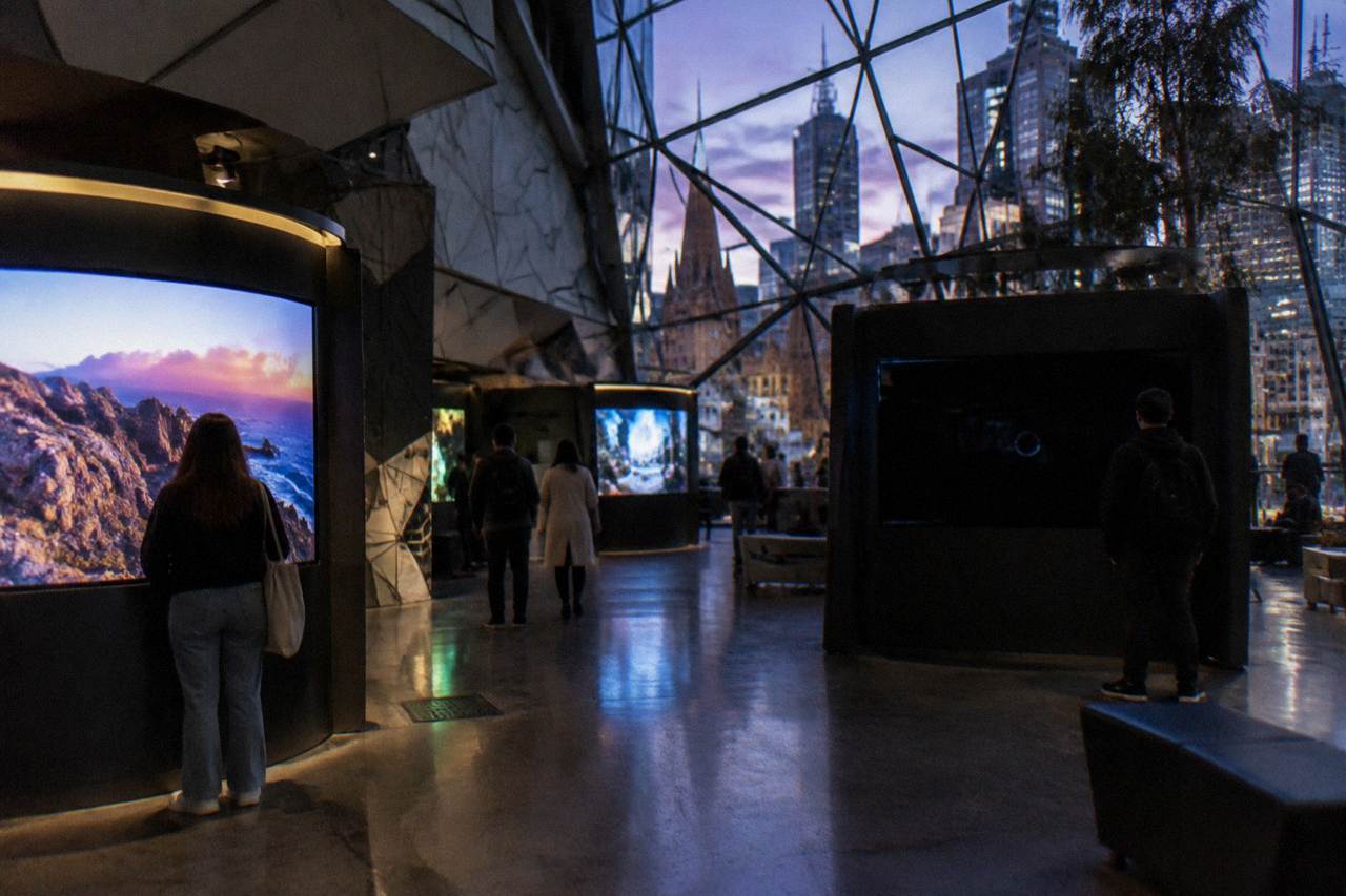 Visitors browsing glowing film and video game exhibits inside the ACMI museum in Melbourne