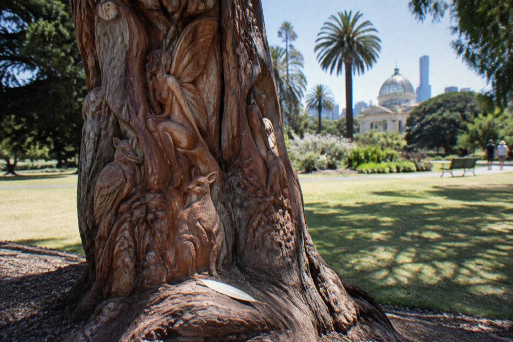 The carved Fairies Tree in Fitzroy Gardens surrounded by green lawn