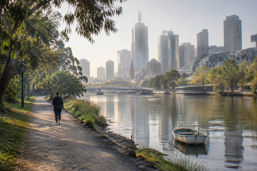 The Yarra River riverside path with the Melbourne skyline behind, walking towards the gardens