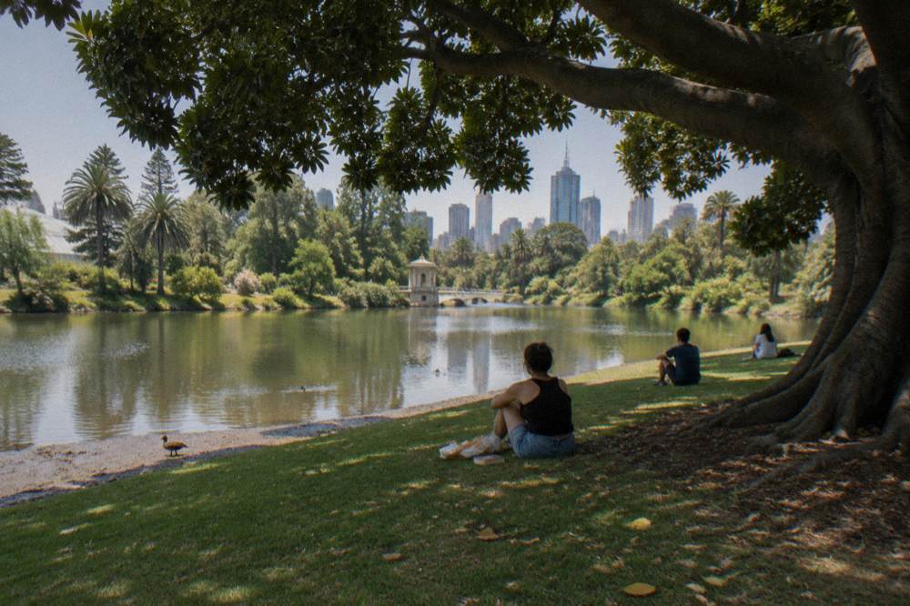 Visitors resting on a lawn beside the ornamental lake in the Royal Botanic Gardens Melbourne