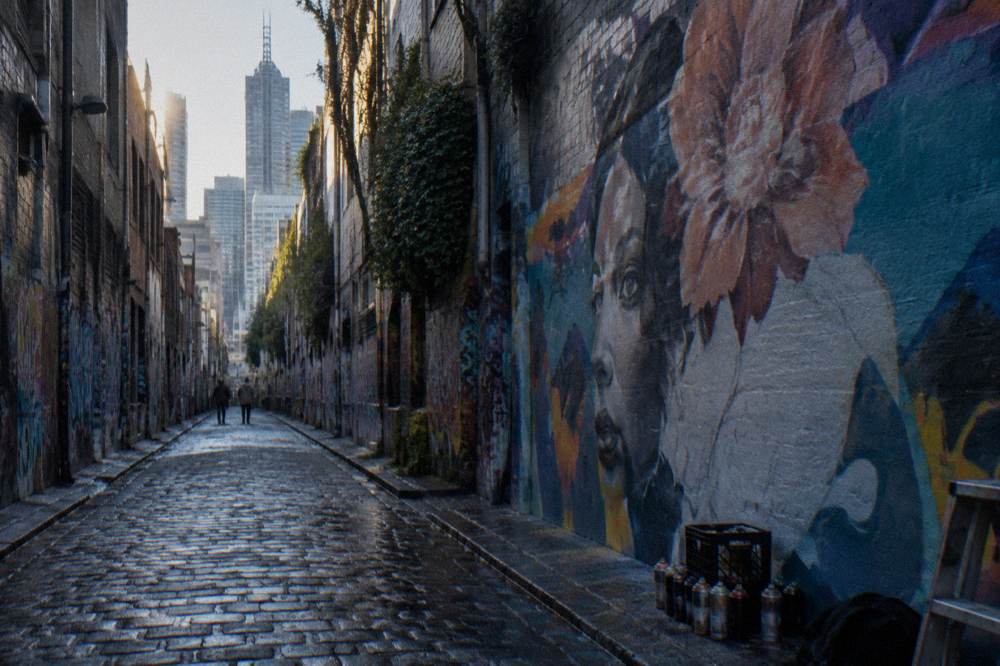 People walking past painted murals in Hosier Lane, a covered Melbourne laneway famous for street art