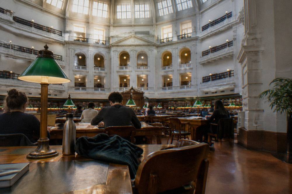 Visitors reading at wooden desks beneath the domed ceiling of the La Trobe Reading Room