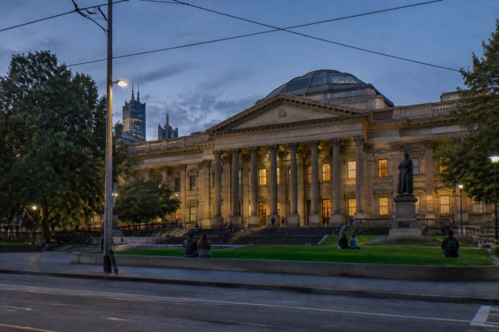 The State Library of Victoria forecourt on Swanston Street with people gathered on the steps