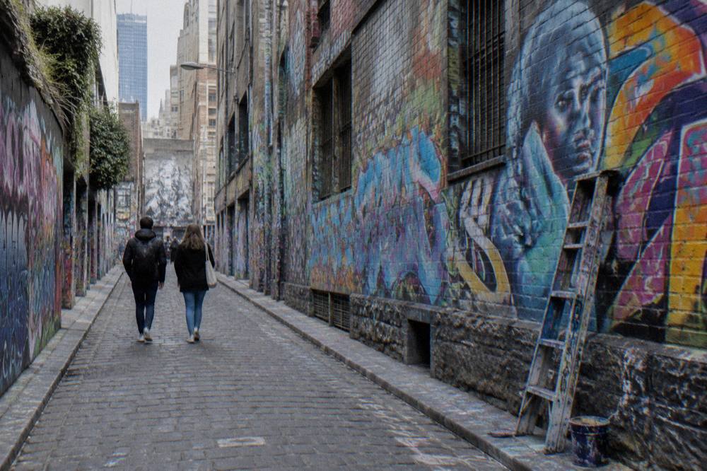 Visitors walking through Hosier Lane past dense colourful street art covering both walls