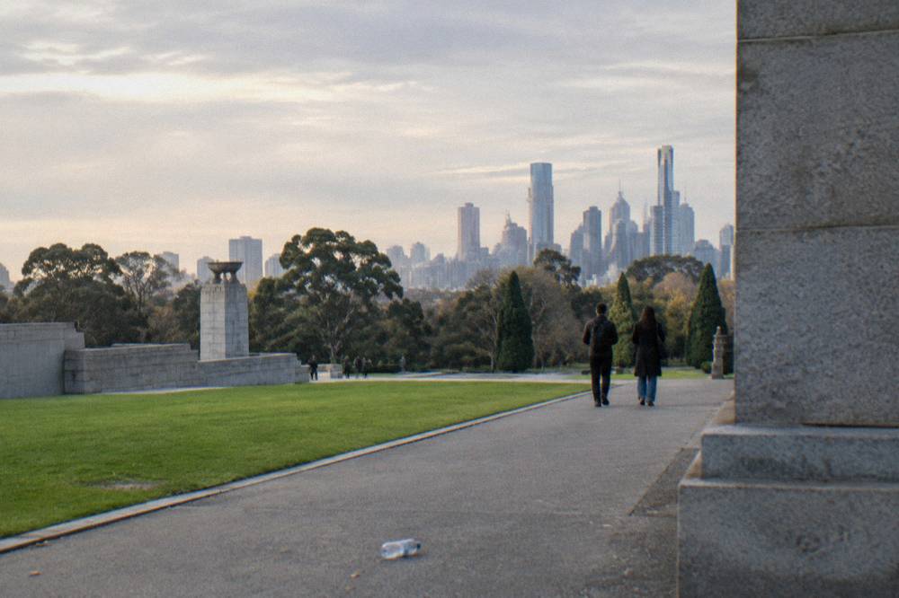 Wide lawns and mature shade trees in a Melbourne park with the city skyline beyond