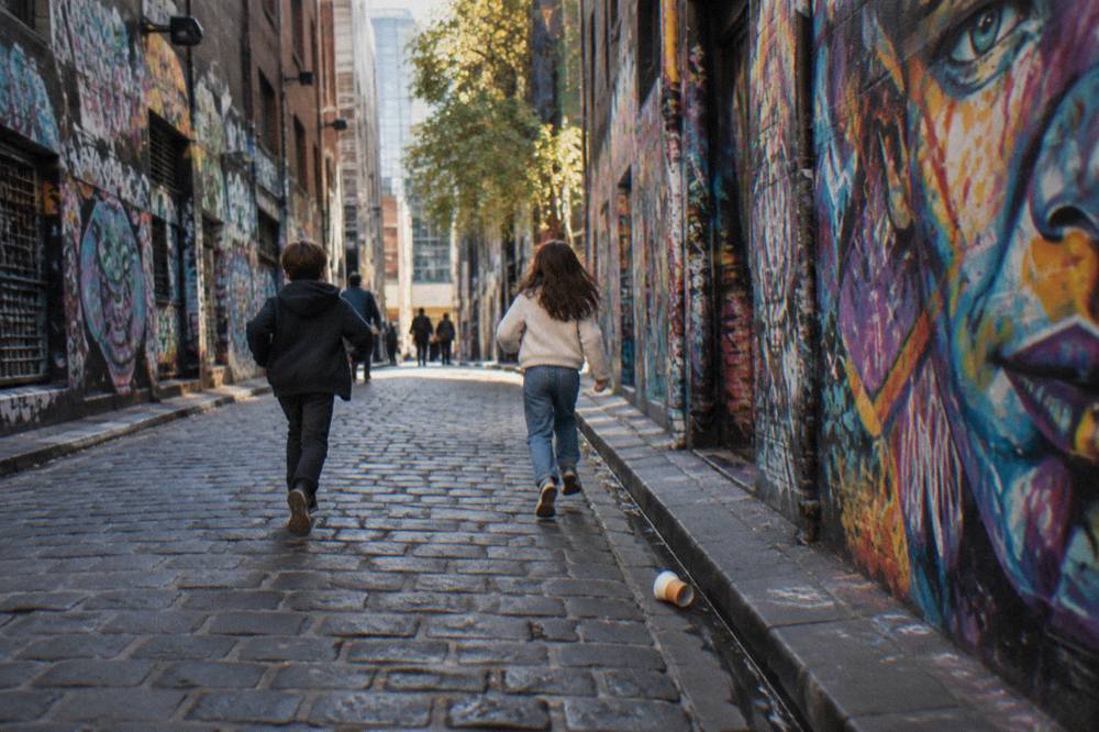 Children exploring a painted laneway in central Melbourne with colourful street art on the walls