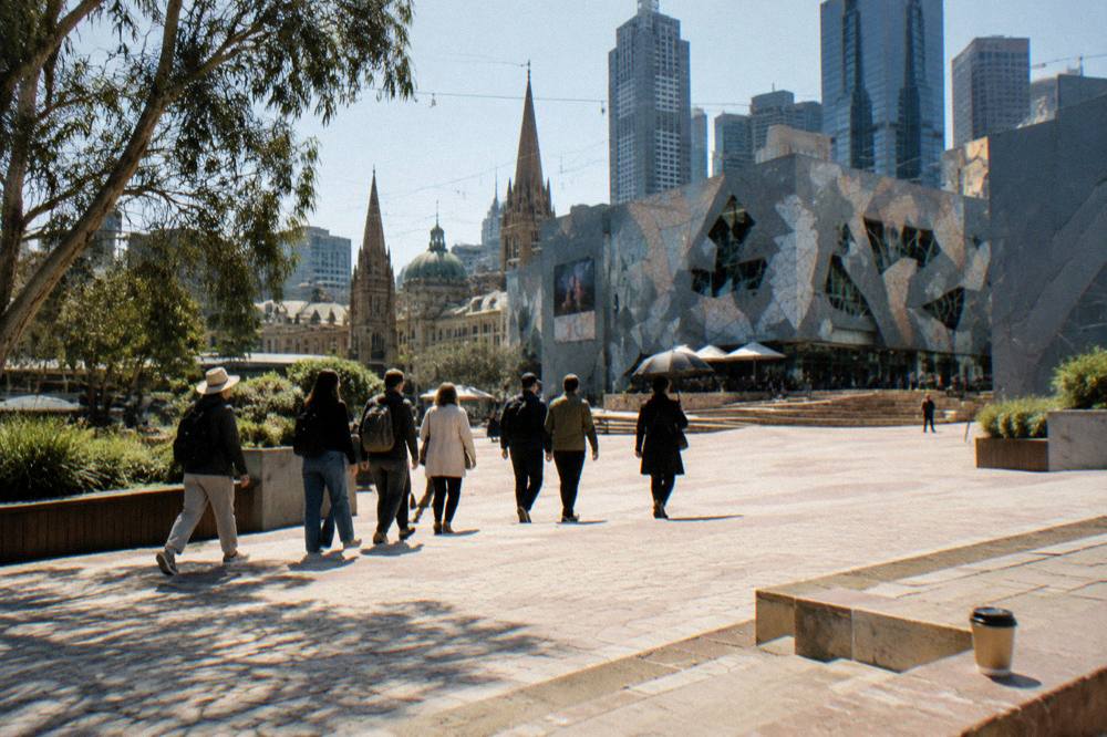 A small group of walkers following a guide with an umbrella across a city square