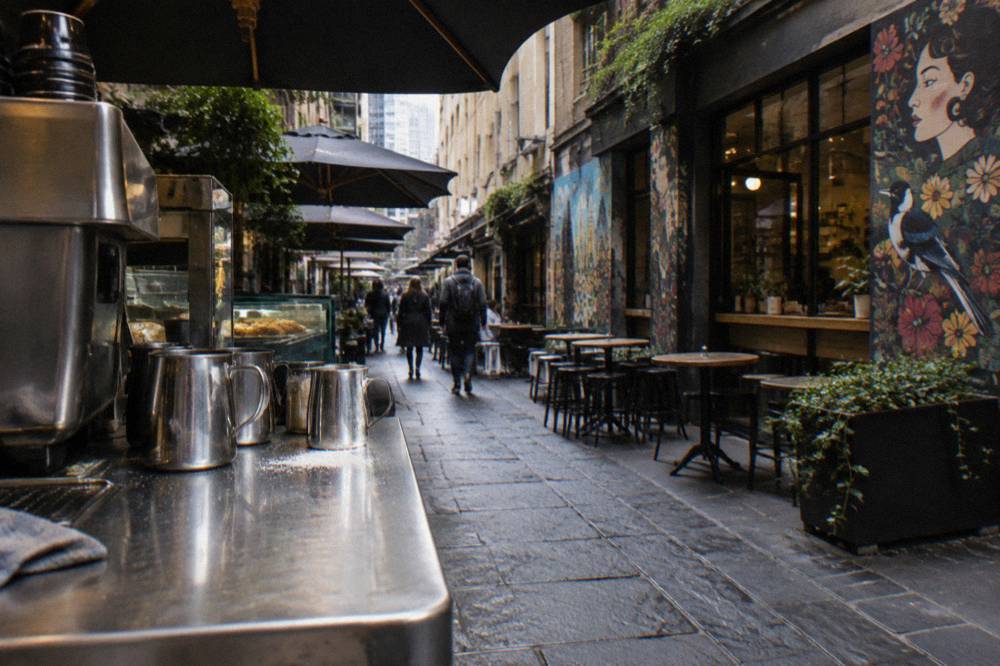 A narrow cafe laneway with small murals painted above shop windows